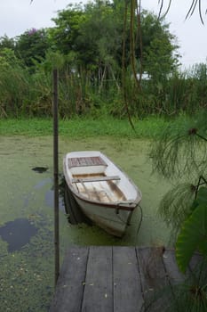 Natural lake landscape with white small fishing boat to the wooden pier