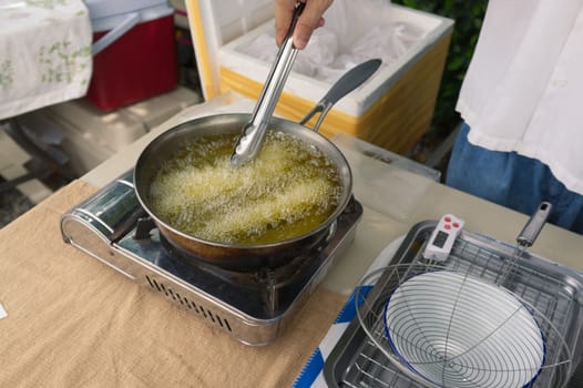 Churros are fried in boiling oil in a frying pan. concept COOKING background .