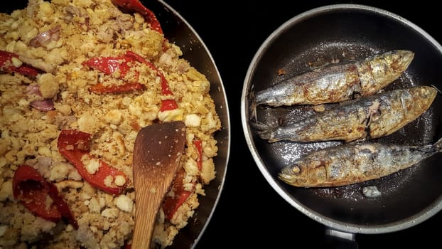 Sapnish migas with roasted sardines cooked in two pans. High view angle