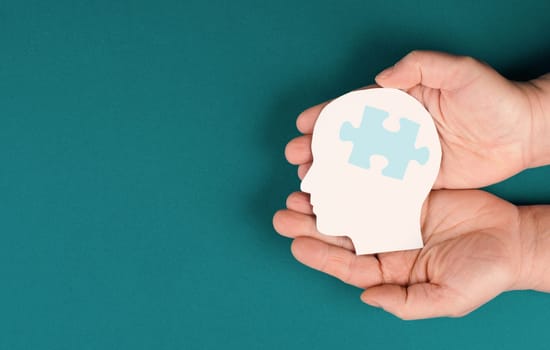 Holding a head with a puzzle piece, mental disease like Autism, Alzheimer, stroke awareness, brainstorming for ideas, memory problems