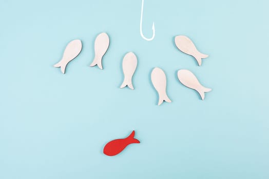 Group of fishes swimming to the fishing rod, red fish makes his own decision and takes a different direction, against the stream symbolic, courage and winner concept