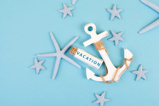 Blue colored summer and holiday background, anchor, sea stars and a glass bootle with the word vacation, travel and tourism concept