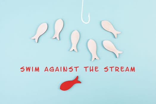 Group of fishes swimming to the fishing rod, red fish makes his own decision and takes a different direction, against the stream symbolic, courage and winner concept