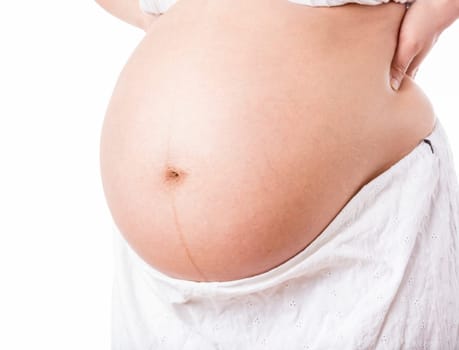 Cutout of a pregnant belly isolated on white background. Focus is on the belly button. Natural skin texture with pregnancy stretch marks. Hands put on the hips. Close up, tightly framed. White skirt.