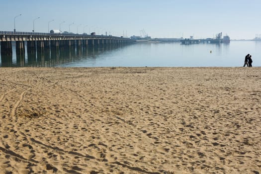 Wooden beach with couple in love at bottom, she is pregnant and he is phoning