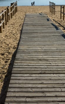 Wooden beach path with couple in love at bottom