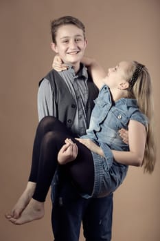 fashion smiling european little long hair blonde girl and her brother posing in atelier
