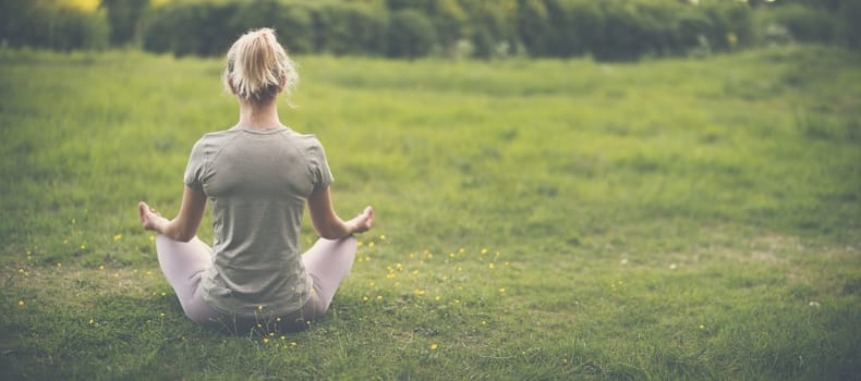 Woman sitting in active wear in lotus position in nature. Concept of healthy lifestyle.