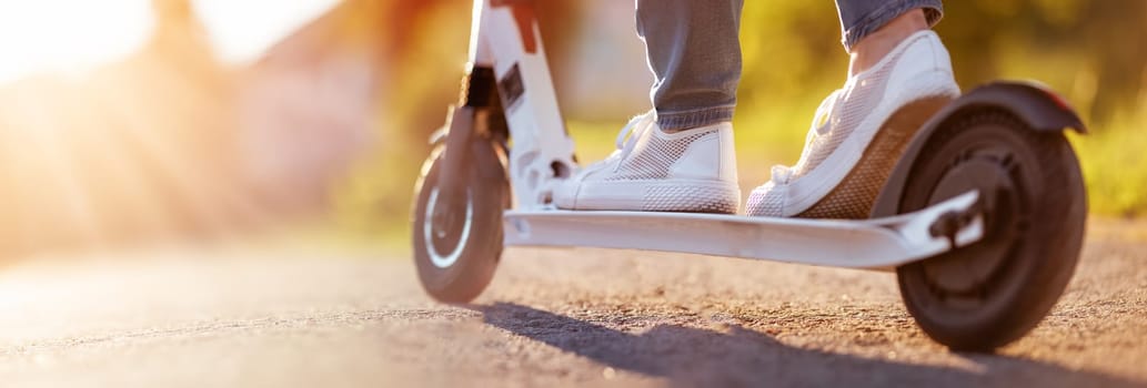 Woman riding on scooter on asphalt road in summer. Close-up view. Concept of city life.