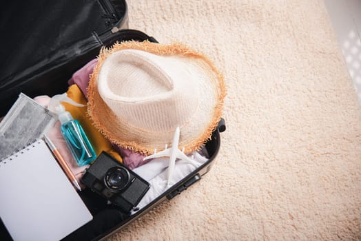 Open suitcase with traveler belongings clothes and accessories of things ready packing to be taken on summer holiday, Travel vacation luggage preparations concept, top view