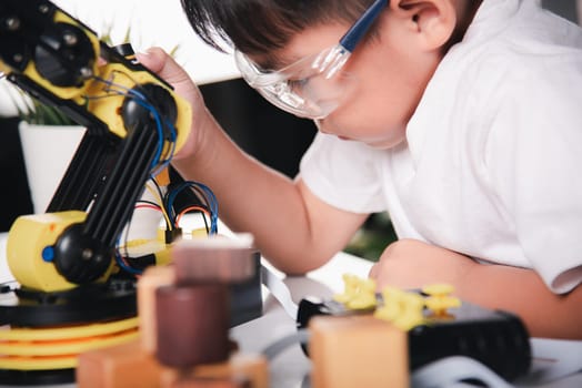Child learning repairing getting lesson control robot arm, Happy Asian little kid boy using screwdriver to fixes screws robotic machine arm in home workshop, Technology future science education concept