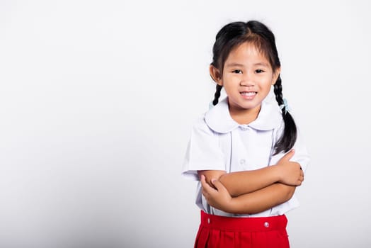 Asian toddler smile happy wearing student thai uniform red skirt stand with arms folded in studio shot isolated on white background, Portrait little children girl preschool crossed arm, Back to school