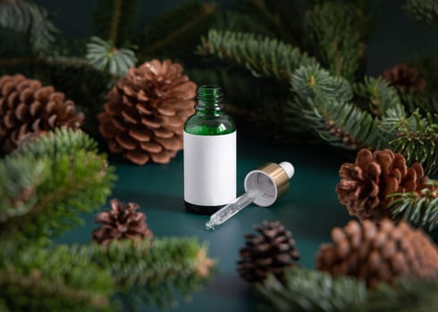 Green Pipette Dropper Bottles with blank label near fir branches and pine cones close up. Brand packaging mockup. Skincare beauty product, cream or serum. Natural cosmetics concept