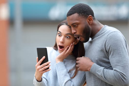 Amazed interracial couple checking phone news