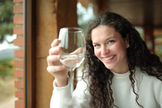 Happy woman holding glass of water in a restaurant