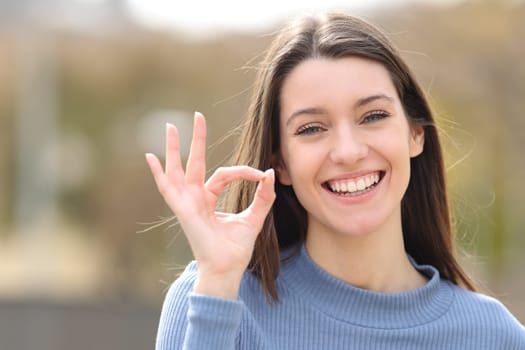 Happy teen gesturing ok sign in a park