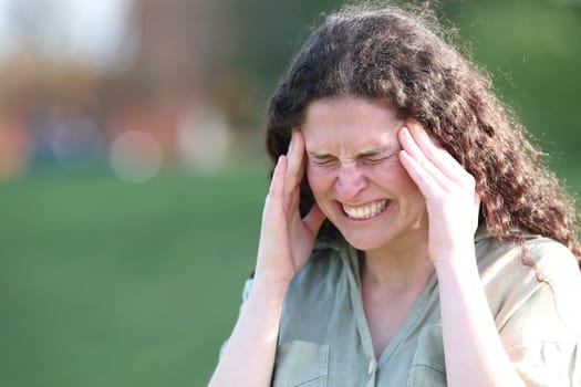 Woman complaining suffering migraine attack in a park
