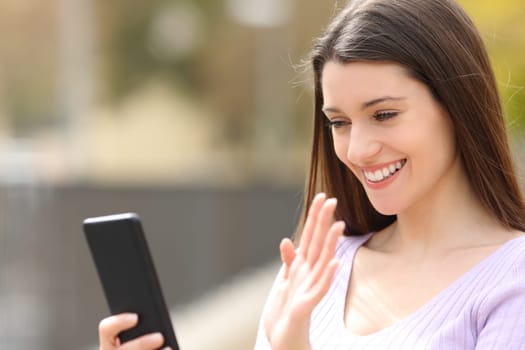 Happy woman greeting during a videocall on phone