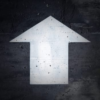 upward pointing white directional arrow on a black background on a concrete wall