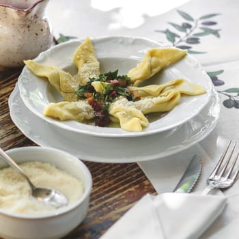 Delicious italian Casoncelli served on rustic wooden table with homemade bread and red wine. Casoncelli alla Bergamasca. Typical italian restaurant. Fresh cooked homemade pasta. .
