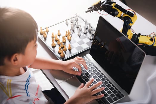 Asian little boy programming code to robot machine arm on laptop for play chess, STEM education E-learning, Funny children learning getting lesson control robot arm, Technology science education