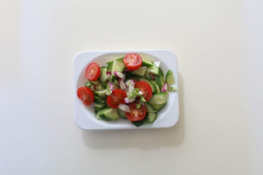 salad of fresh cucumbers, cherry tomatoes and green onions on a square dish