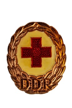 Potsdam, Germany - MAY 06, 2022. Badges, orders and medals from GDR (DDR). Close-up of a National Defence Badge of the German Red Cross in bronze. Clipping path. Macro isolated on white.