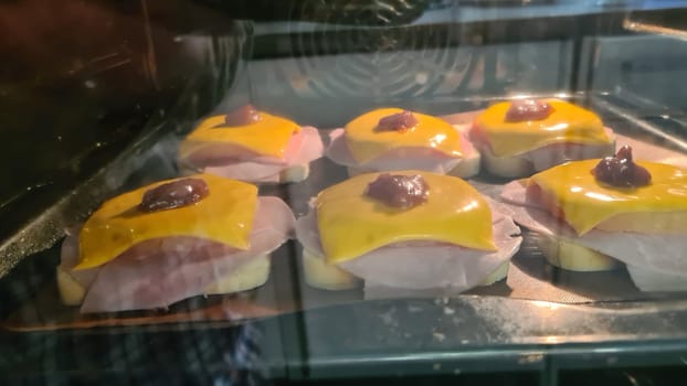Open faced sandwiches with fried chicken breast and fried onions with pineapple and cheese on a baking sheet