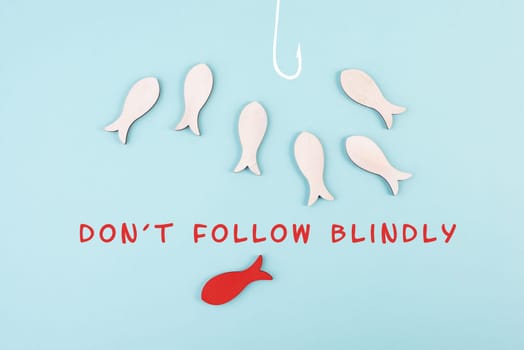 Group of fishes swimming to the fishing rod, red fish makes his own decision and takes a different direction, do not follow blindly, courage and winner concept
