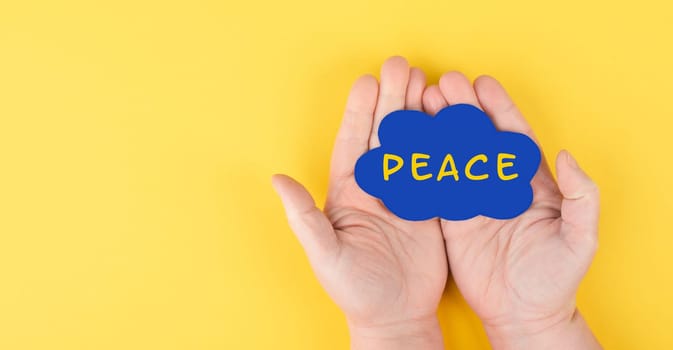 Holding a blue cloud with the word peace in the hands, stop war, support Ukraine, living peaceful together, color of ukrainian flag