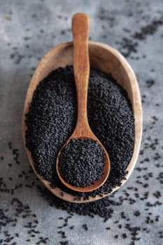 Indian spice Black cumin (nigella sativa or kalonji) seeds in bowl with spoon on grey table top view. Traditional medicine, healthy and vegetarian food concept.