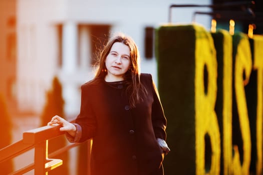 Woman in the street looking at camera in sunshine. Businesswoman at sunset. Selective focus.