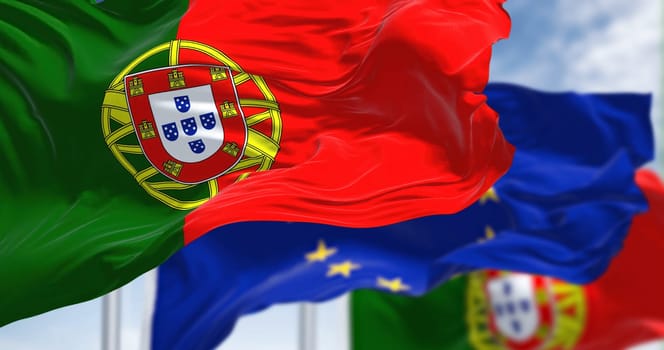 Detail of the national flag of Portugal waving in the wind with blurred european union flag in the background on a clear day. Democracy and politics. European country. Selective focus.
