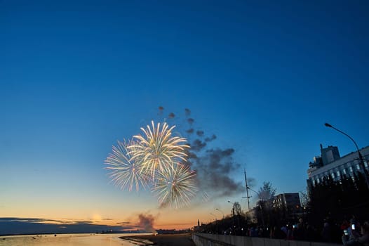Colorful fireworks on the background of the sky on the river bank. High quality photo