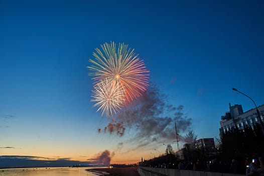 Colorful fireworks on the background of the sky on the river bank. High quality photo