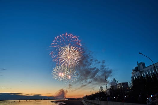 Colorful fireworks on the background of the sky on the river bank. High quality photo