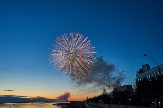 Colorful fireworks on the background of the sky on the river bank. High quality photo