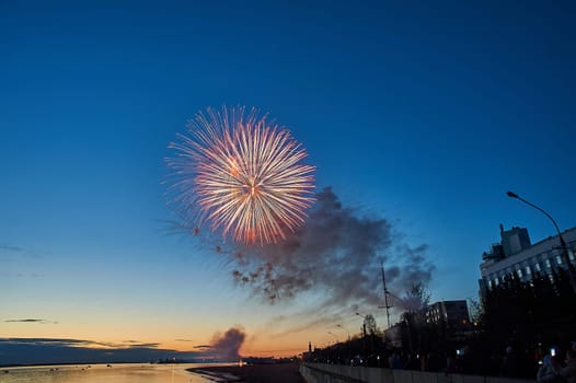 Colorful fireworks on the background of the sky on the river bank. High quality photo