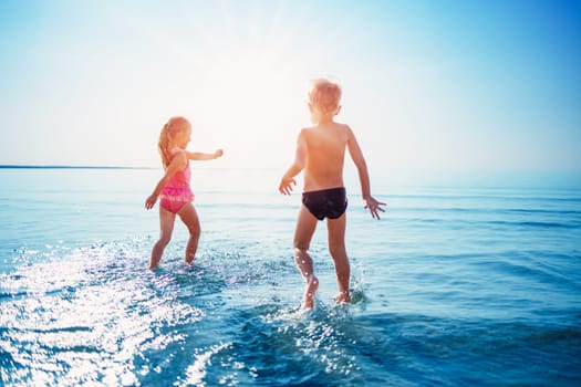 Happy children playing together in the sea in summer. Concept of the family vacation and traveling.