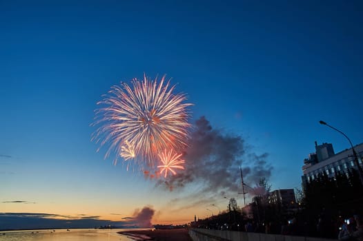 Colorful fireworks on the background of the sky on the river bank. High quality photo