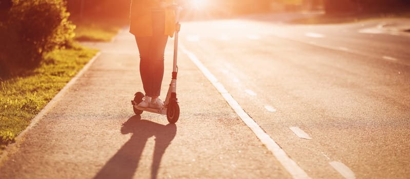 Woman riding on scooter on asphalt road in summer. Concept of city life.