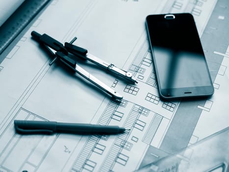 Architectural project, rulers, cell phone and pen.