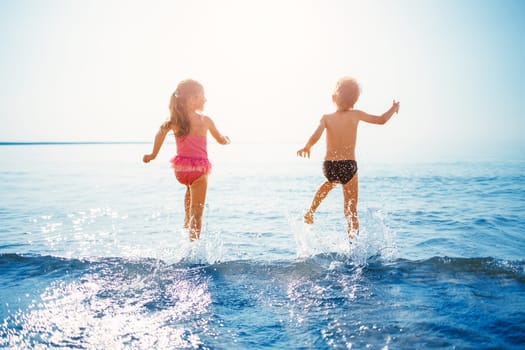 Happy children playing together in the sea in summer. Concept of the family vacation and traveling.