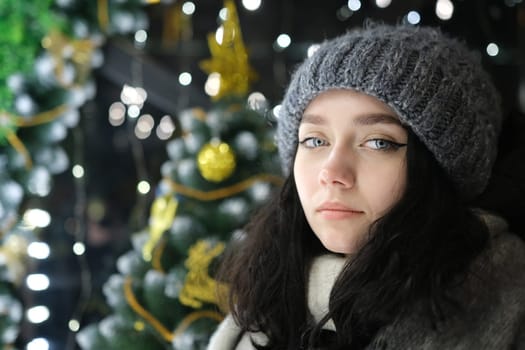 young beautiful happy smiling girl posing Christmas tree on background. Model wearing stylish clothes. Happy New Year with lights