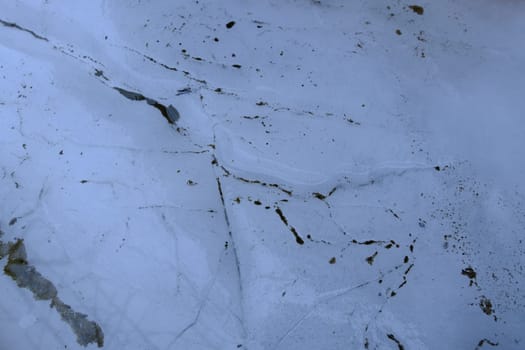 Close-up of frozen water surface with green algae at the bottom of a pond, winter day. Frozen water texture.