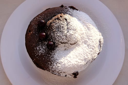 Homemade sweet cholocate cake with powdered sugar and berrys served on white plate top view