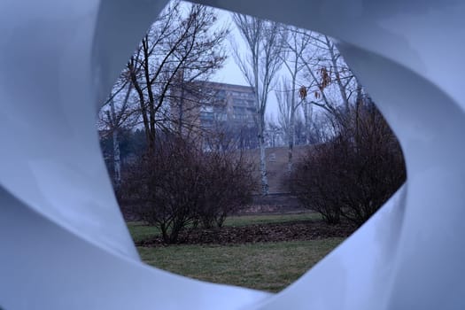 Multisrorey residential building in Mariupol, Ukraine. 22.02.2022 Veiw from white art gallery object in park. Building inside white figure.