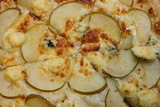 Sliced Pizza with pear, gorgonzola and honeycomb honey dipper on baking paper over Top view, Close up.