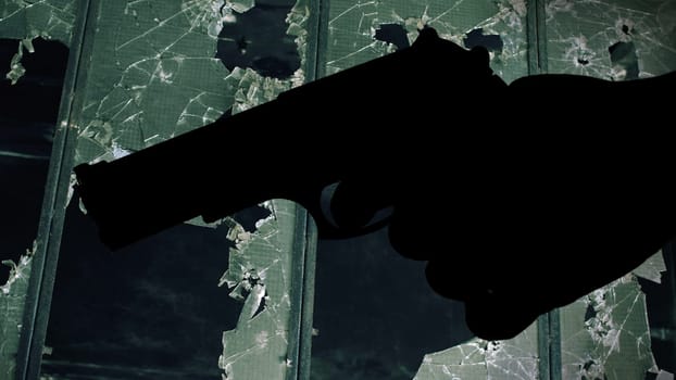 Gun silhouette against broken window crime concept