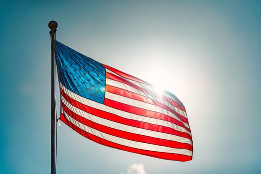 US american flag and blue cloudy sky with clouds in background